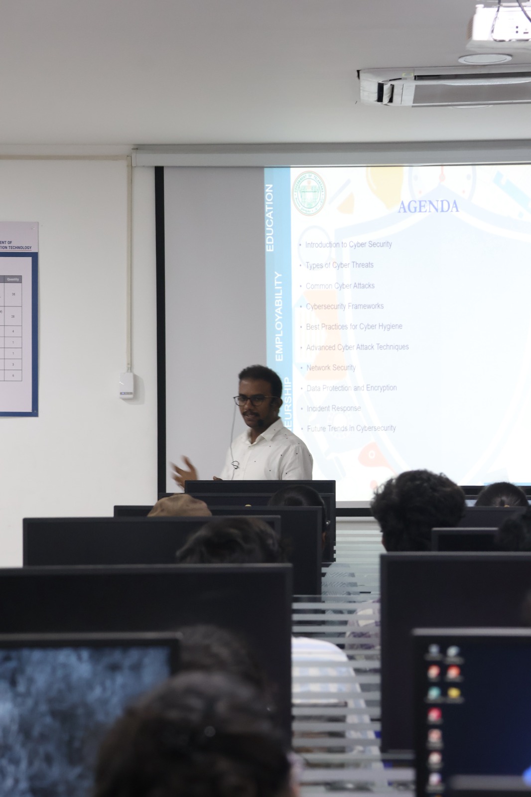 A TechM4India mentor presenting a cybersecurity agenda slide to students at computers